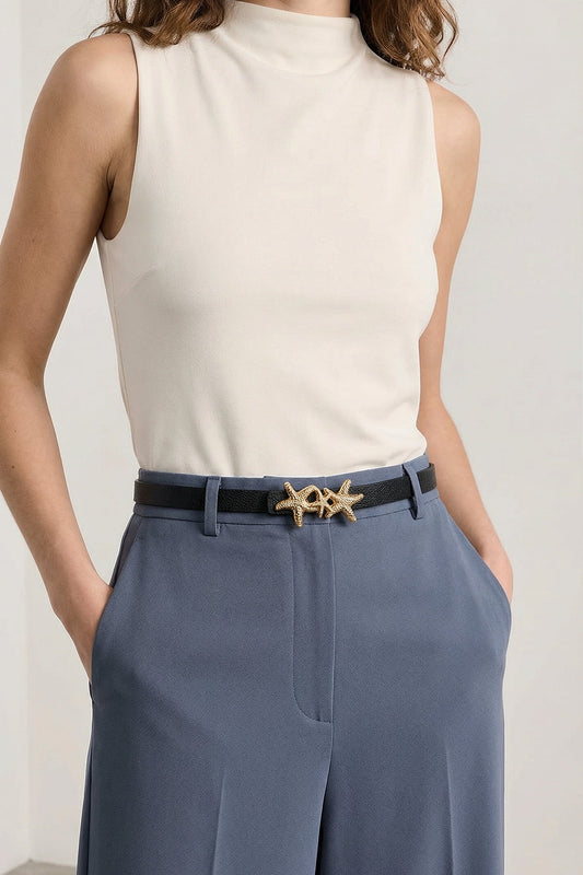 Milleniva beyaz kolsuz bluz ve mavi pantolon ile kombinlenmiş, altın deniz yıldızı tokalı siyah kemer.