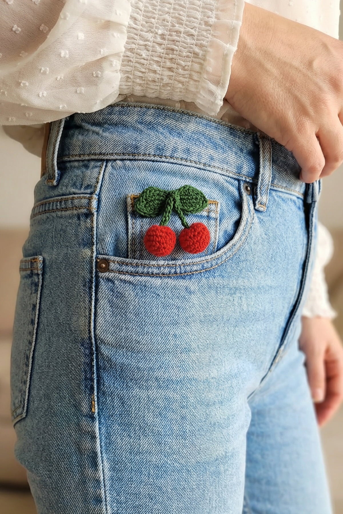 Kot pantolon cebinde Milleniva el örgüsü broş modeli. Kiraz figürlü sevimli tasarım kadın örgü broş aksesuarı.